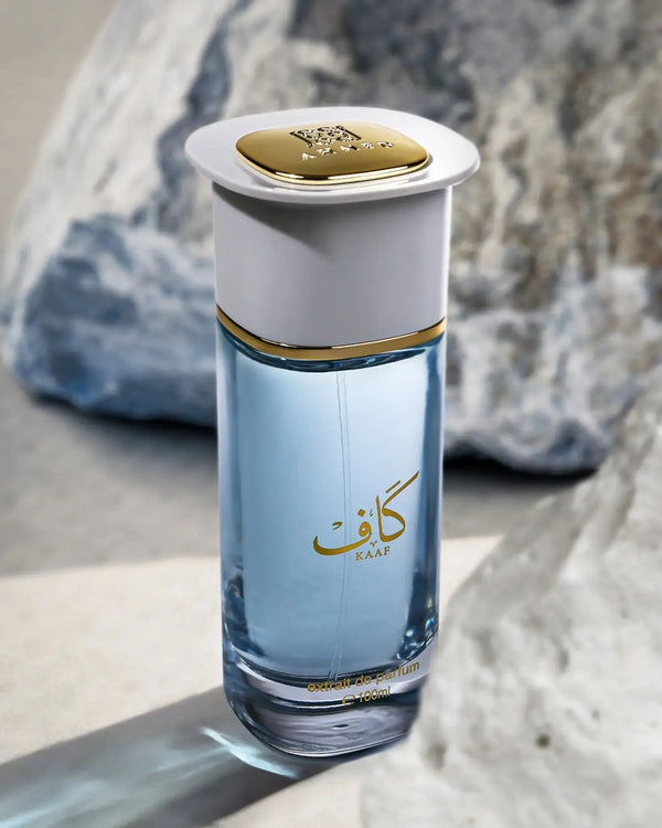 Perfume bottle with gold cap and Arabic text on a textured surface
