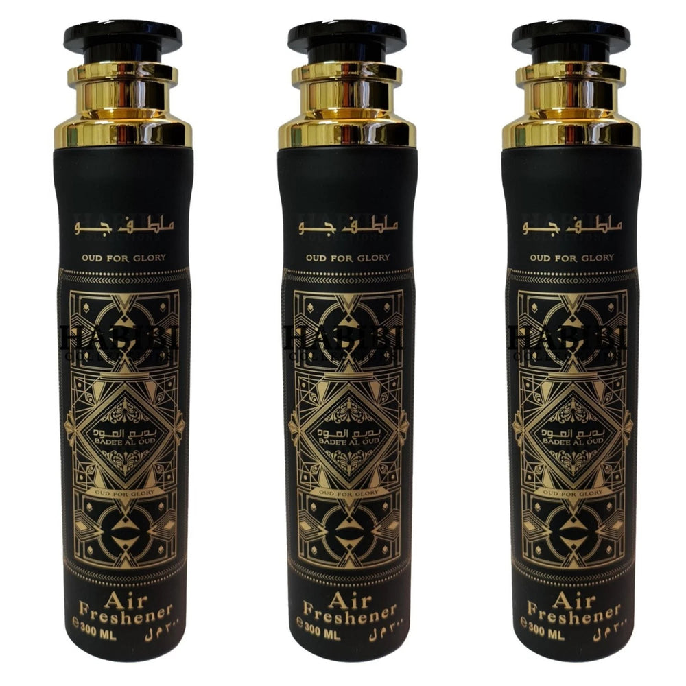 Three black cylindrical air freshener bottles with gold caps and intricate gold geometric patterns, labeled 'OUD FOR GLORY' and 'Air Freshener', shown on a white background.Lattafa Bade'e Al Oud Room Spray 300ml