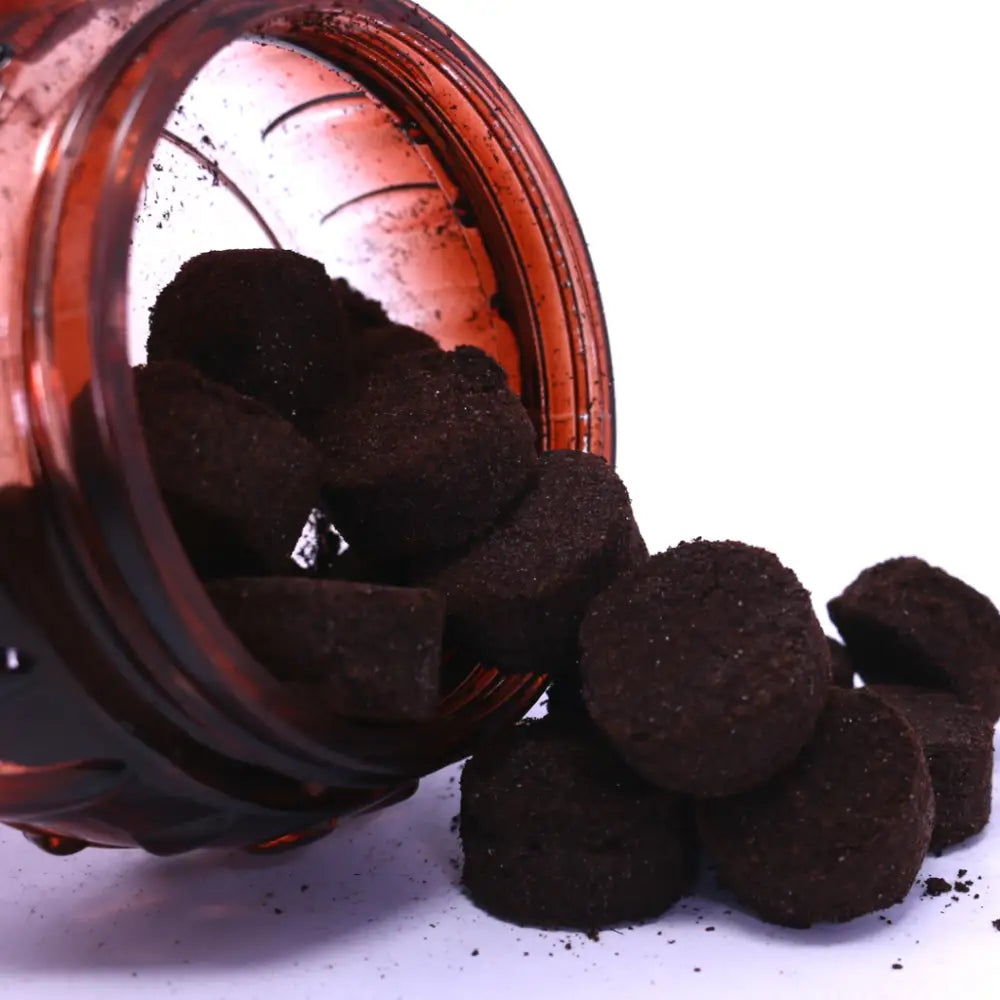 Brown powder in a glass jar with some spilling out on a white background
