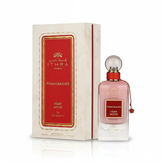 A pink glass perfume bottle with a red cap and clear stopper labeled ithra dubai musk pomegranate eau de parfum 100ml