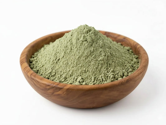 A mound of finely ground green hadrami sidr powder in a rustic wooden bowl for natural hair cleanser and stronger-looking hair