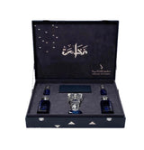 An open dark blue presentation box containing a clear faceted glass vessel in the center and two small dark blue bottles on either side, photographed on a plain white background.Al Fakhama Luxury Fragrance Gift Set 6 Pieces – Dkhoon AlEmiratia