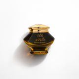 A dark amber glass cosmetic jar with a shiny gold lid, featuring gold Arabic and English text that reads 'Bakboub Kuwaiti' on the front, set against a clean white background with a soft shadow. Almas Perfumes Kuwaiti Bakhoor 40g – Gulf Incense