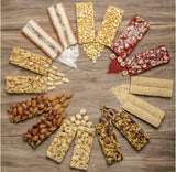 An assortment of colorful nut and seed energy bars arranged in a circular pattern on a rustic wooden background.