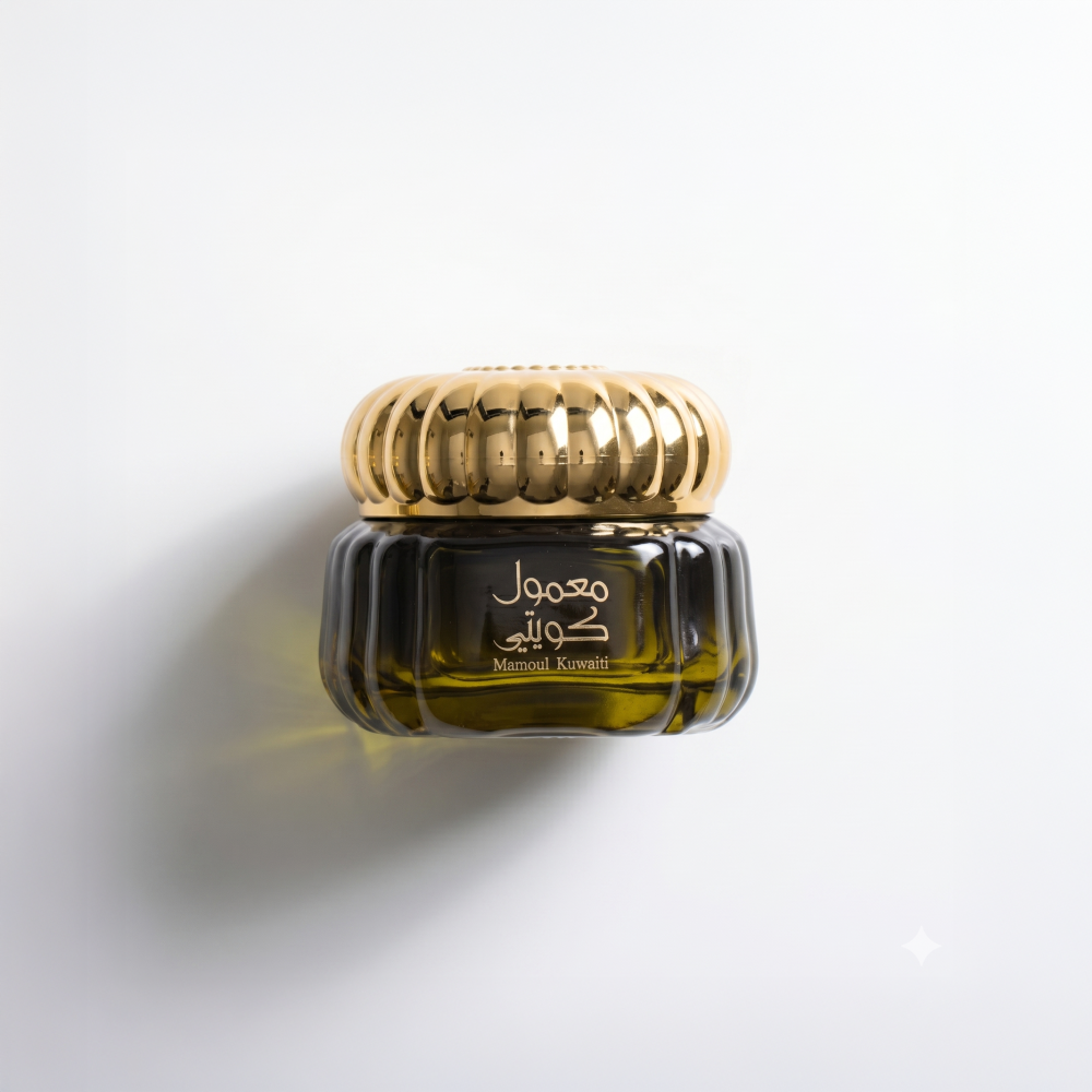A small dark amber glass jar with a shiny gold ribbed lid, featuring Arabic and English text on the front, set against a clean white background with a soft  shadow. Mamoul Kuwaiti Bakhoor 60g – Gulf Incense