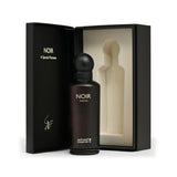 A dark brown glass perfume bottle labeled 'NOIR PARFUM' stands in front of an open black presentation box with a cream-colored insert. The box lid is printed with 'NOIR A Special Moment' and a small signature-like mark.Noir – Woody Fruity EDP 150ml – Al Majed Oud