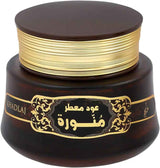 A dark brown cosmetic jar with a gold band around the neck and a gold decorative label featuring Arabic text, on a plain white background.Oud Muattar Munawwara Bakhoor 35g – Khadlaj