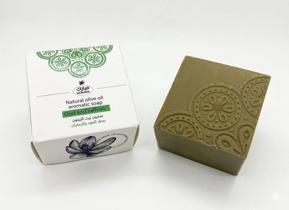 Green soap bar with decorative patterns next to its packaging on a white background