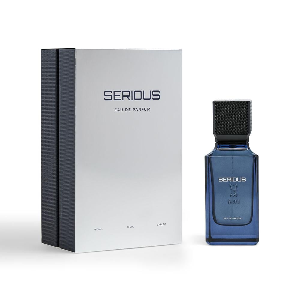 A bottle of Serious Eau de Parfum next to its white and dark gray packaging box on a clean white background.Serious – Amber Fougère EDP 100ml – Al Majed Oud