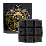 Black soap bar with a decorative box featuring Arabic text and a portrait on a white background