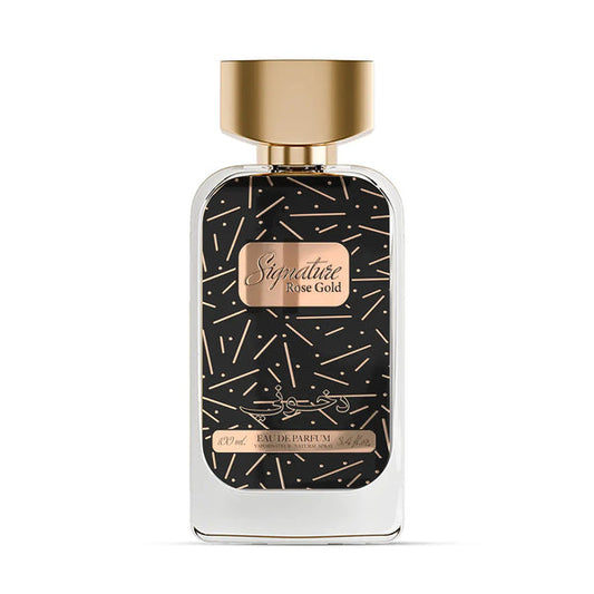 A 50ml bottle of Signature Rose Gold Eau de Parfum, featuring a clear glass body, a black label with gold confetti patterns, and a shiny gold cap, set against a plain white background.Signature Rose Gold – Spicy Amber EDP 100ml – Dkhoon Emirates