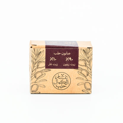 Soap bar with a brown packaging featuring olive tree design and Arabic text on a white background