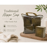 Traditional Aleppo Soap 4-Bar Family Pack on a wooden tray with olive branches and towels.