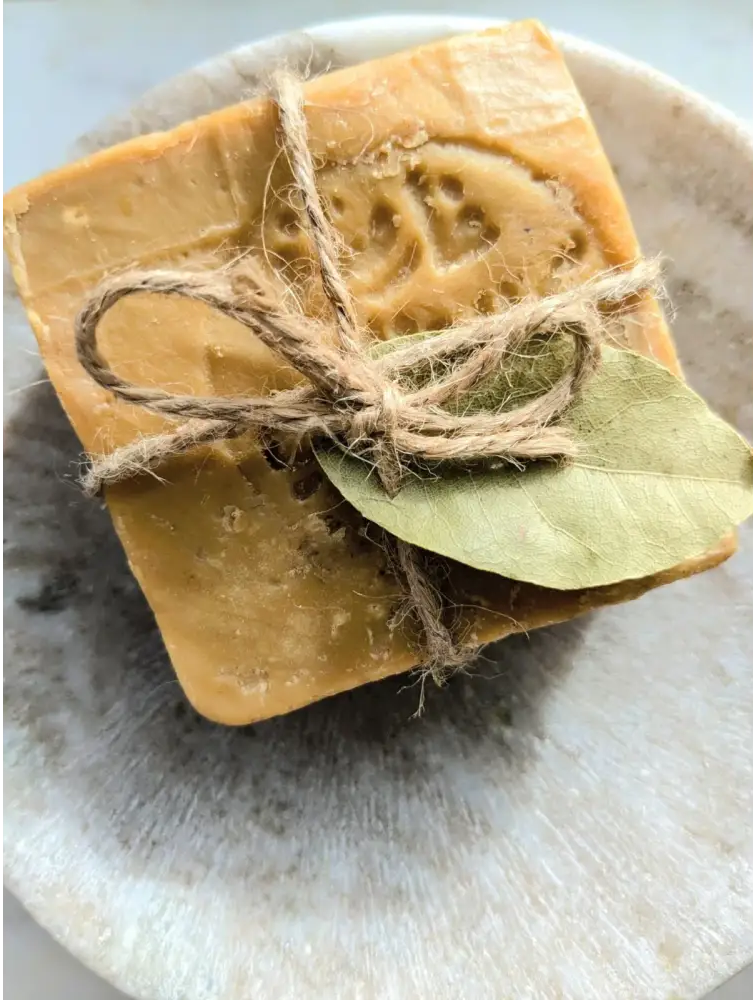 Bar of soap with twine and a leaf on a stone surface