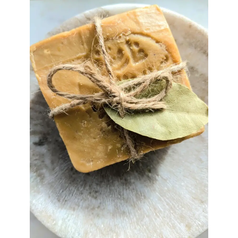 Bar of soap with twine and a leaf on a stone surface