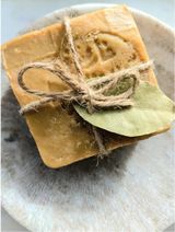 Bar of soap with twine and a leaf on a stone surface