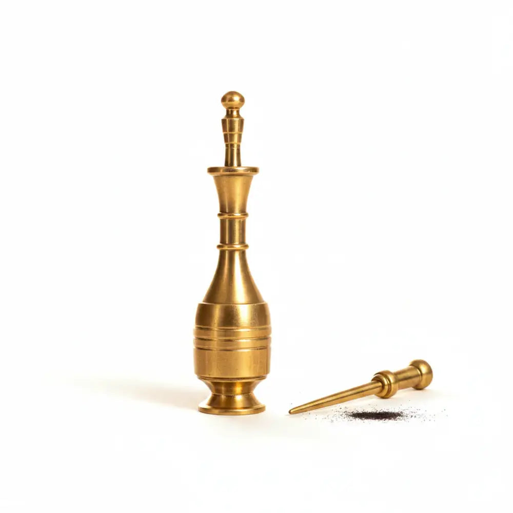 Brass pepper grinder with a small amount of ground pepper on a white background