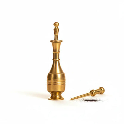 Brass pepper grinder with a small amount of ground pepper on a white background
