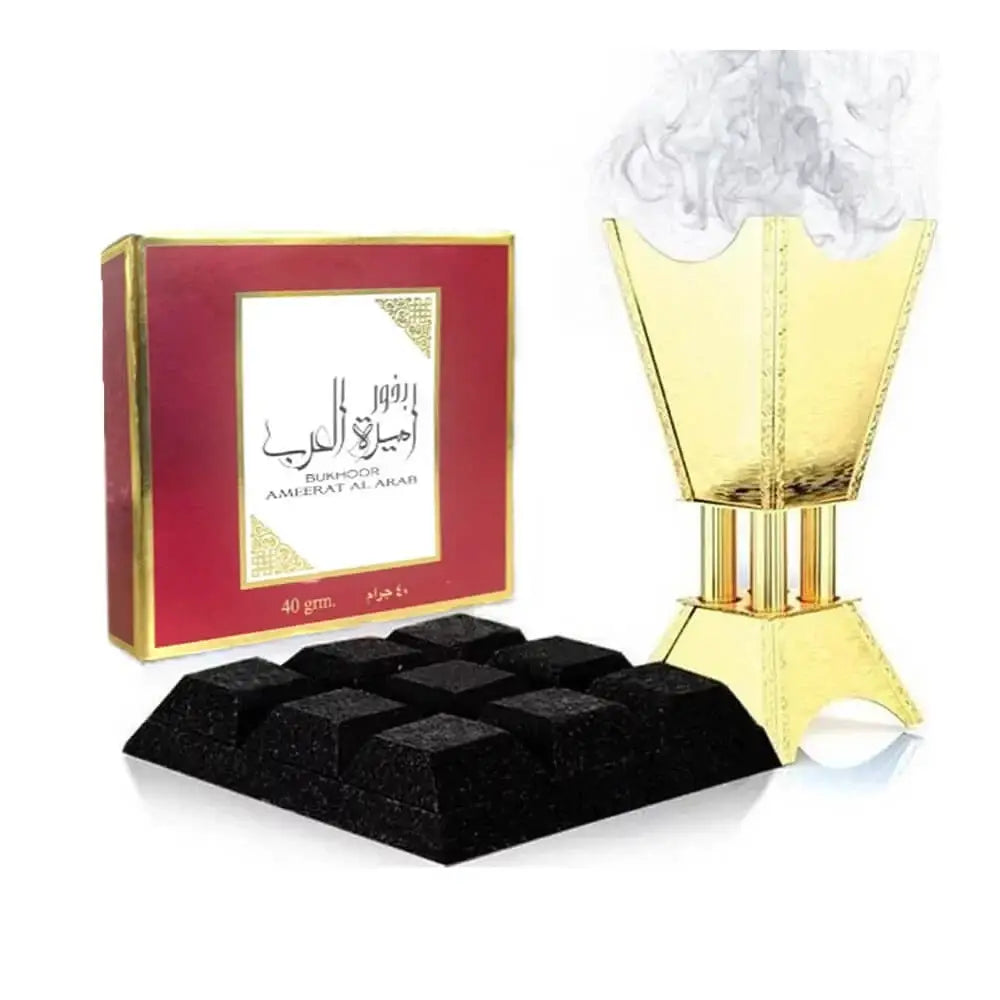 Golden incense burner with intricate details and smoke next to red bukhoor ameerat al arab box and black charcoal cubes by ard al zaafaran