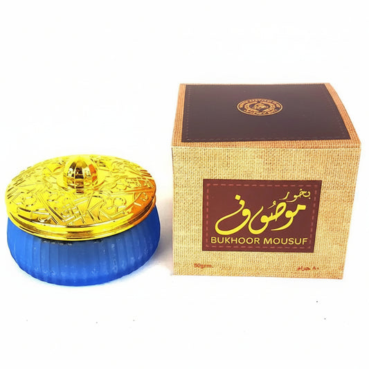 Blue container with gold lid and 'Bukhoor Mousuf' packaging on a white background