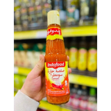 A vibrant orange Indofood hot chili sauce bottle 340ml with a yellow cap and Arabic script on a red label held in hand