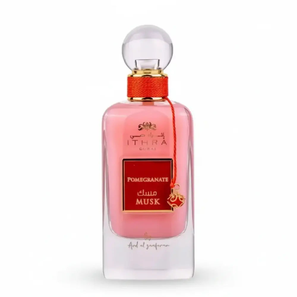 A pink glass perfume bottle of ithra dubai musk pomegranate eau de parfum 100ml with gold cap and red ribbon tie