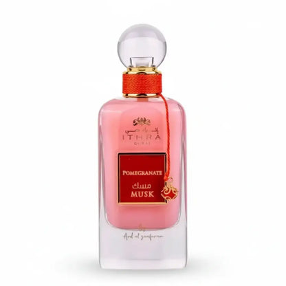 A pink glass perfume bottle of ithra dubai musk pomegranate eau de parfum 100ml with gold cap and red ribbon tie