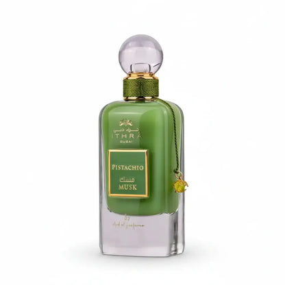 A sleek emerald green glass perfume bottle with gold accents labeled ithra dubai musk pistachio eau de parfum 100ml