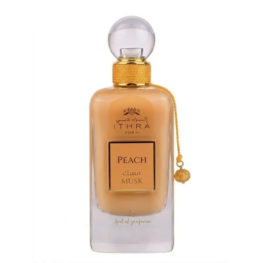 A sleek transparent glass perfume bottle with golden cap containing amber ithra dubai musk peach fragrance