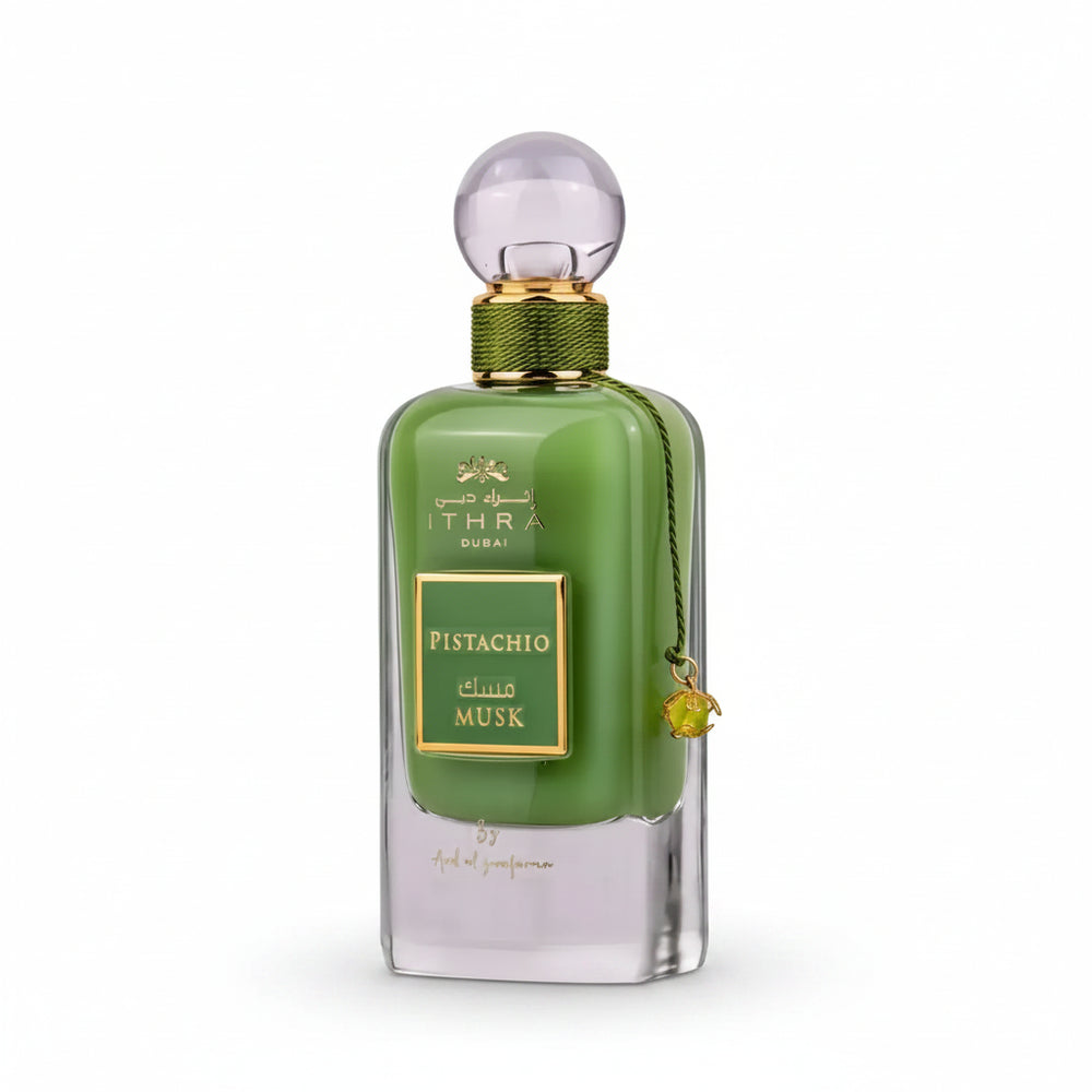 A sleek emerald green glass perfume bottle with gold accents labeled ithra dubai musk pistachio eau de parfum 100ml