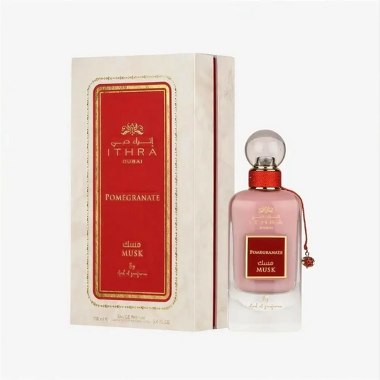 A pink glass perfume bottle with a red cap and clear stopper labeled ithra dubai musk pomegranate eau de parfum 100ml
