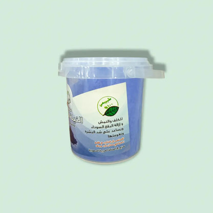 A blue plastic container of moroccan blue nila powder 30g with a clear lid labeled in arabic and green leaf imagery