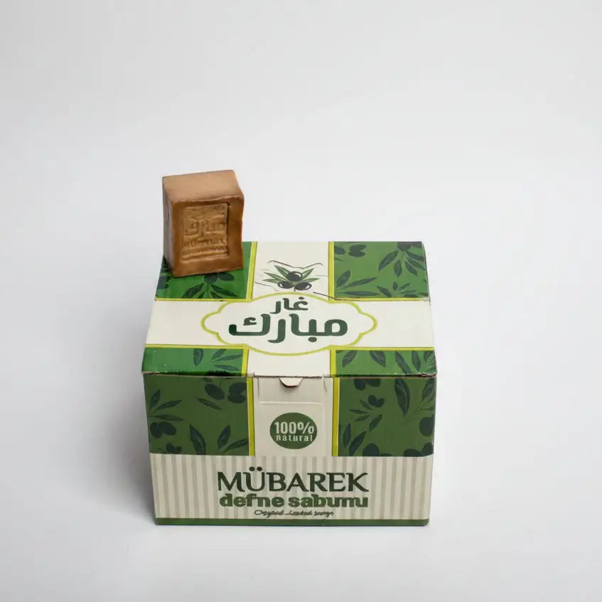 Green and white box with a brown bar of soap on top against a white background