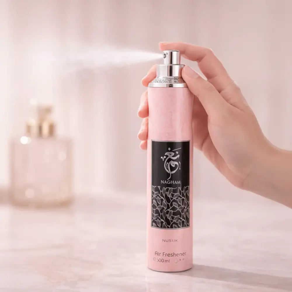 Hand holding a pink air freshener spray bottle labeled 'NACHANI' against a blurred background.