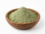 A mound of finely ground green hadrami sidr powder in a rustic wooden bowl for natural hair cleanser and stronger-looking hair