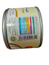 Canister of baby formula with label held by a hand on a dark surface
