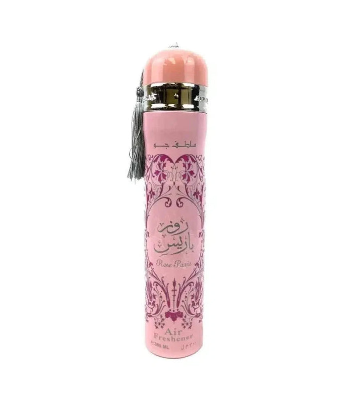 A pink cylindrical perfume bottle with Arabic calligraphy on the front, a pink cap, a gold collar, and a gray tassel, shown on a plain white background.