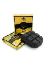 A gold and black box labeled 'Gold Oud' with a gold foil wrapped packet and a dark charcoal-colored textured oud root resting in front, set against a plain white background.