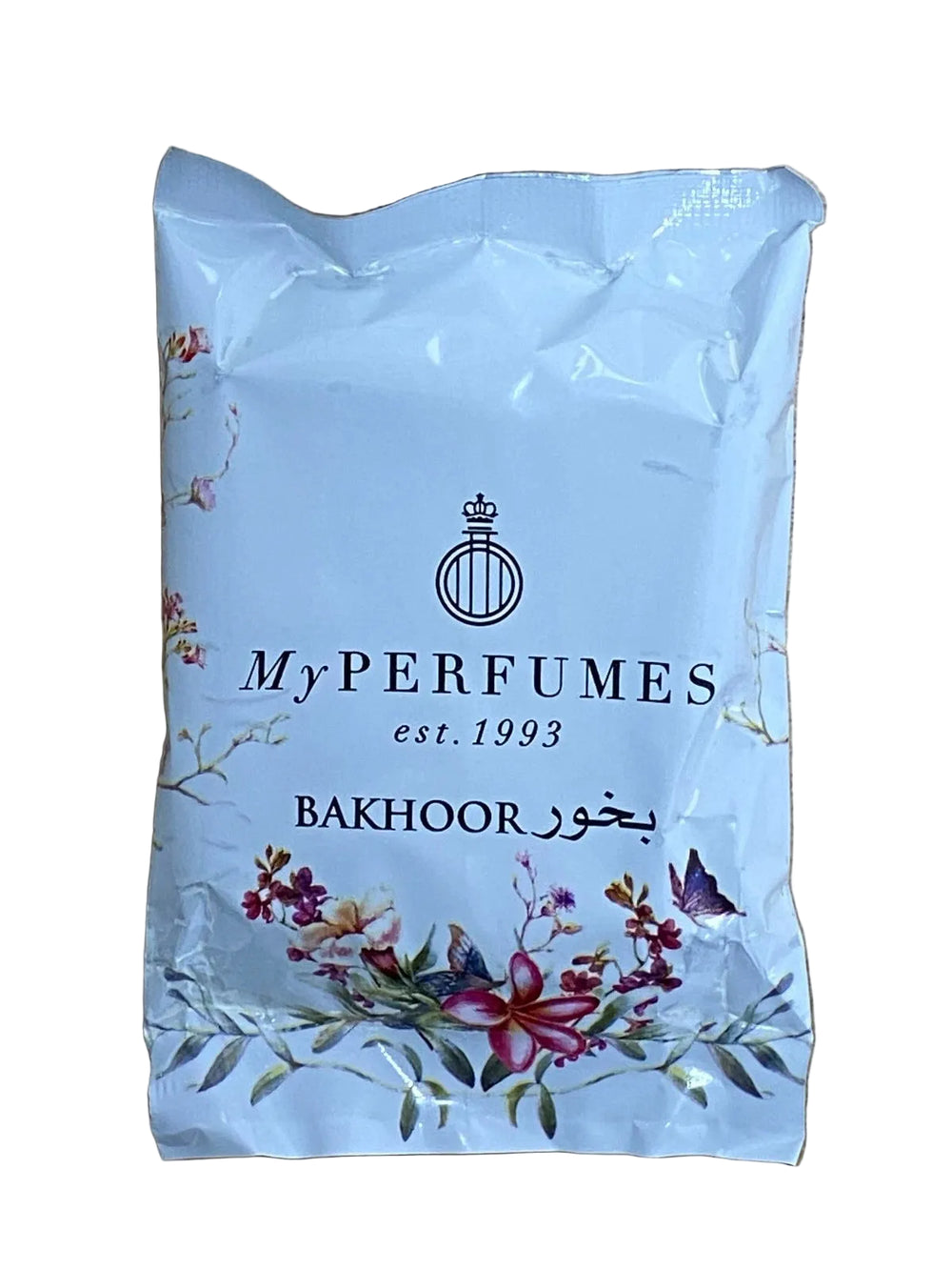 A white plastic pouch of My Perfumes Bakhoor fragrance, featuring black text and floral illustrations, resting on a light brown wooden surface.