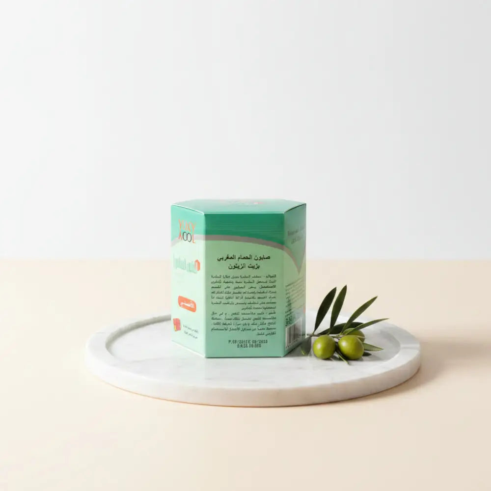 Hand holding a green box with text, likely a product packaging, in front of a keyboard.