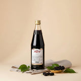 A clear glass bottle of vimto arabic fruit cordial syrup filled with dark red liquid and a gold cap