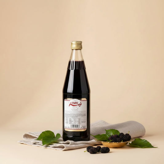 A clear glass bottle of vimto arabic fruit cordial syrup filled with dark red liquid and a gold cap